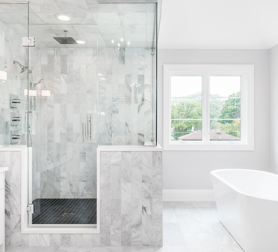 Marble tiled bathroom with a glass shower and freestanding tub
